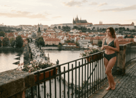 Prague escort model in black lingerie on terrace with Charles Bridge view